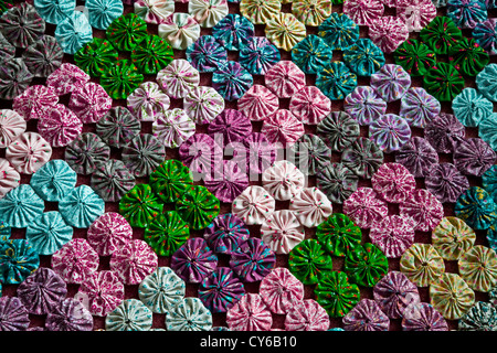 Close up unusual vintage handmade fabric pattern squares and blocks of a yo yo quilt blocks, New Jersey, USA quilt squares on bed Stock Photo