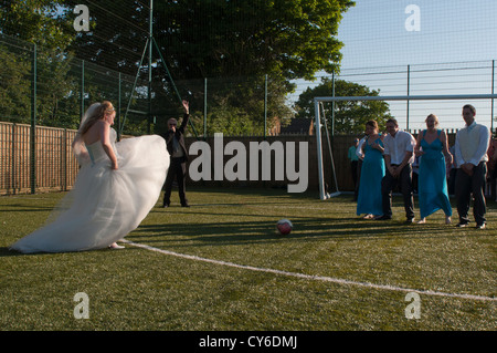 Model Released - quirky shot of a bride playing football at a wedding Stock Photo