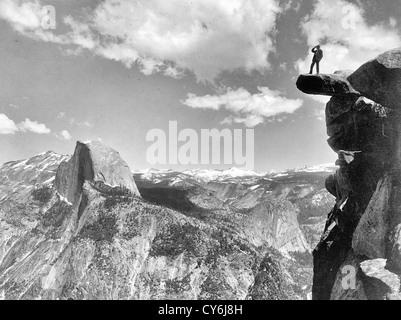 Overhanging Rock, Glacier Point - a man standing on Glacier Point, facing Half Dome in Yosemite National Park, California, circa 1901 Stock Photo