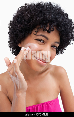 Smiling woman putting some cream on her face Stock Photo