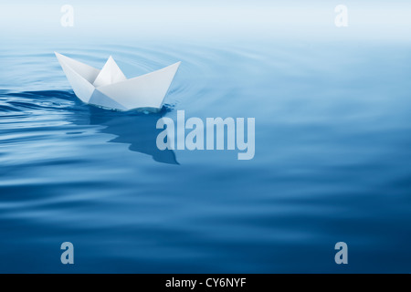 paper boat sailing on blue water surface Stock Photo