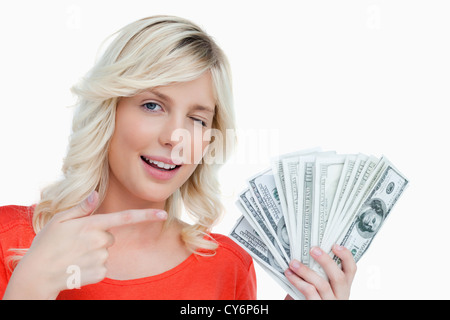 Woman winking an eye while pointing her finger on dollar notes Stock Photo