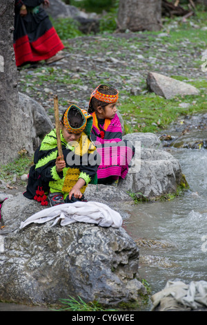 Kalash girls washing clothes in the stream running through the village of Balanguru, Rumbur Valley, Chitral, Khyber-Pakhtunkhwa, Pakistan Stock Photo