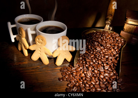 Gingerbread men standing around two hot coffee cups Stock Photo