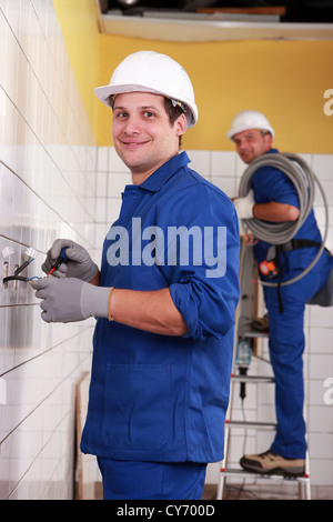 Electricians working in a tiled room Stock Photo