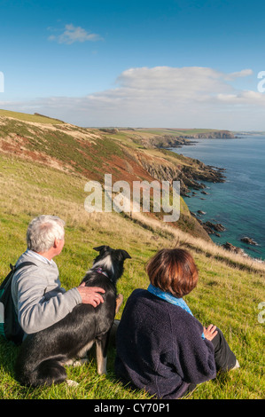 A couple and their dog enjoying the view on the South Devon coastal path east of Plymouth on a late sunny summer evening. UK Stock Photo