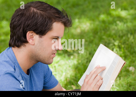 Young serious man reading a book while sitting in a park Stock Photo