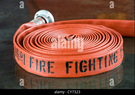 A rolled up firehose on the wet floor in a firestation used by firefighters Stock Photo