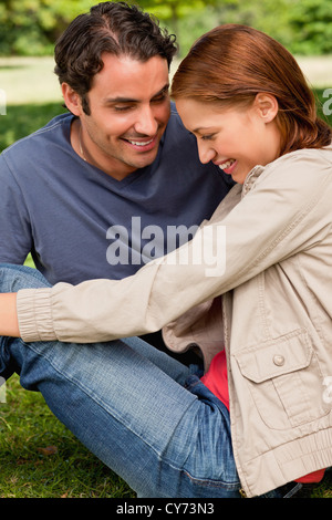 Two friends look happily towards the ground as they sit next to each other Stock Photo