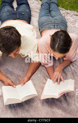 Man and a woman reading while lying on a blanket Stock Photo