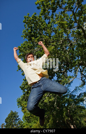 Man raising both of his arms and both of his legs as he jumps in celebration Stock Photo