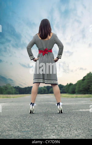 a woman in a black and white dress is standing on a street Stock Photo