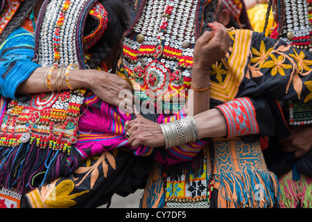 Kalash women wearing headdresses dancing, from behind, at the Anish Brun Village Charso (dancing ground), Kalash Joshi (Spring Festival), Bumburet Valley, Chitral, Khyber-Pakhtunkhwa, Pakistan Stock Photo