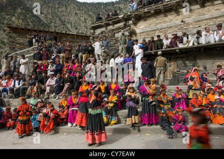 Kalash women and girls overlooked by security forces at the Grum Village Charso (dancing ground), Kalash Joshi (Spring Festival), Rumbur Valley, Chitral, Khyber-Pakhtunkhwa, Pakistan Stock Photo