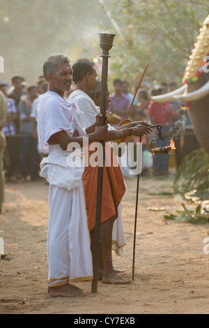 Priests holding flaming lamps in front of caparisoned elephants wearing golden Nettipattam at the Goureeswara Temple Festival, Cherai, near Kochi (Cochin), Kerala, India Stock Photo