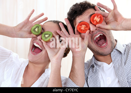 Covering his eyes with a couple slices of kiwi and tomato Stock Photo