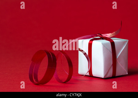 White gift box with red ribbon isolated on red color background Stock Photo