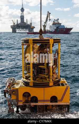 ROV with oil rig and supply boat in the background Stock Photo