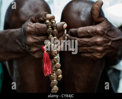 Old Indian mans hand holding Indian Rudraksha / Japa Mala prayer beads Stock Photo