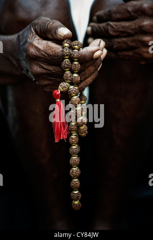 Old Indian mans hand holding Indian Rudraksha / Japa Mala prayer beads Stock Photo
