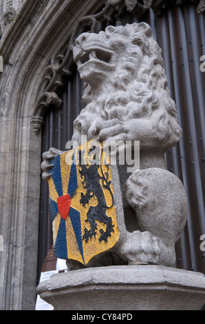 Carved stone lion holding a shield bearing the coat of arms of Flanders Stock Photo