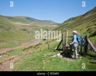 A female walker admiring the view to the hills of Moel Sych and Cadair Berwyn in the Berwyn Mountains, North Wales Stock Photo