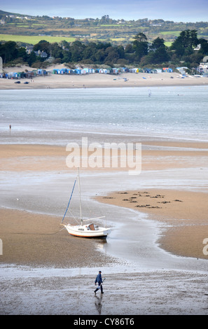 A fisherman carrying a spade to dig for lugworms crosses the sands on Borth Fawr or Main Beach at Abersoch on the Lleyn Peninsul Stock Photo