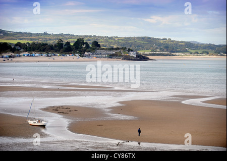 A fisherman carrying a spade to dig for lugworms crosses the sands on Borth Fawr or Main Beach at Abersoch on the Lleyn Peninsul Stock Photo