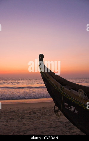 Vertical view of the bow of a fishing long boat on the beach at sunset in Kovalam. Stock Photo