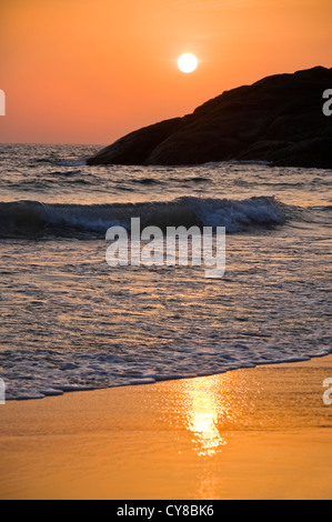 Vertical view of the sun setting over the crashing waves in Kerala, India. Stock Photo