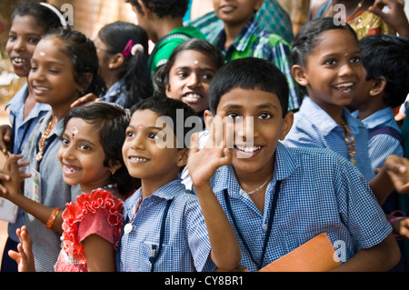 Horizontal view of a group of school kids in smart uniform smiling and waving. Stock Photo