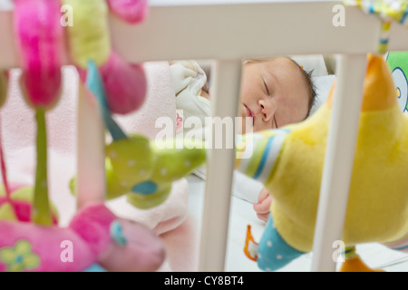 Sleeping newborn baby,view through the fence at the crib. Stock Photo
