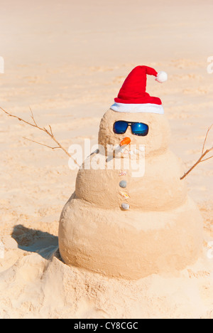 Perfect Sandman With Carrot Nose And Sunnies, perfectly shaped Snowman made from sand with Santa hat. Stock Photo