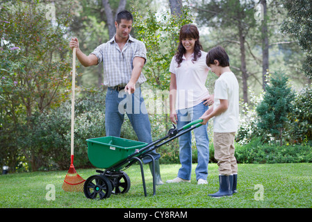 Father and two children working together in yard