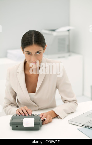 Woman using adding machine in office Stock Photo