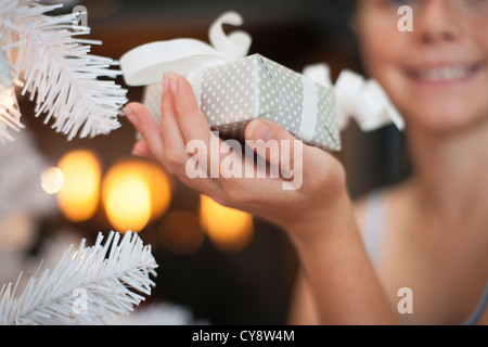 Girl's hand holding Christmas present next to Christmas tree Stock Photo