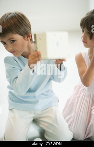 Little boy shaking gift box curiously Stock Photo