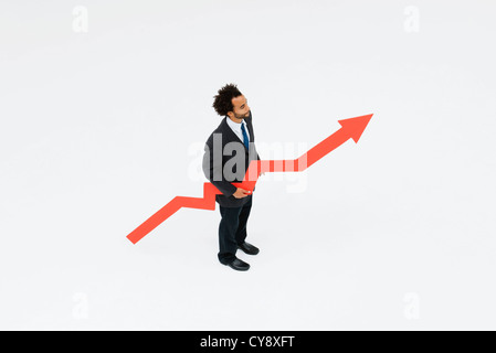Businessman with arrow pointed upward projecting financial growth Stock Photo