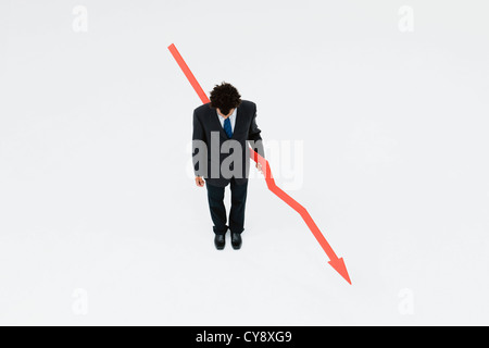 Businessman with arrow pointed downward, projecting financial loss Stock Photo