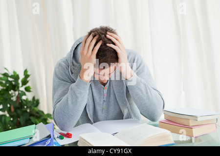 Distressed student in front of his books Stock Photo