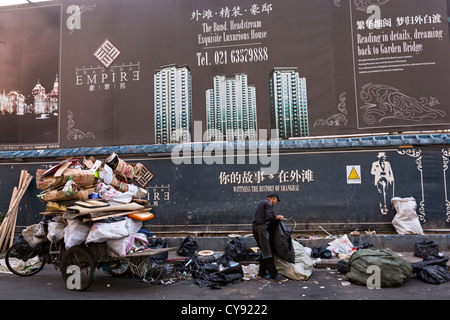 A street cleaner recycles paper in front of a luxury development in Shanghai, China Stock Photo