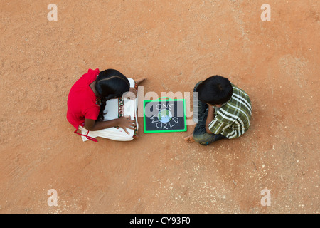 Indian village girl and boy with ONE WORLD written on a chalkboard in a rural indian village. Andhra Pradesh, India Stock Photo
