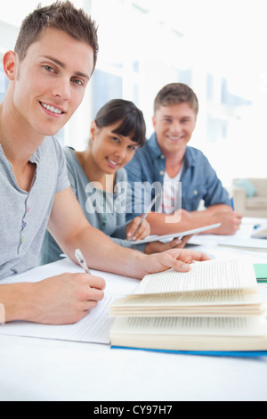 A close up of three studying friends as they look into the camera Stock Photo