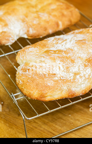 Home-made ciabatta cooling down on a rack after having been removed from an oven Stock Photo