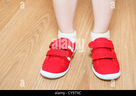 Children legs in wrong feet shoes wearing standing on the floor Stock Photo