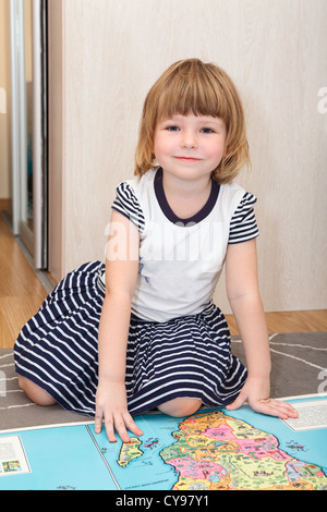 Diligent Russian girl sitting on the floor with world children atlas book Stock Photo