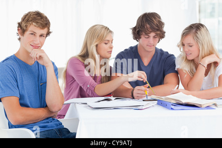 Four friends studying as one guy looks at the camera and smiles Stock Photo