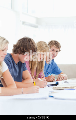 Close up of a student smiling as he looks at the camera while studying with friends Stock Photo