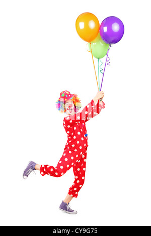 Full length portrait of a male clown holding balloons and flying isolated on white background Stock Photo