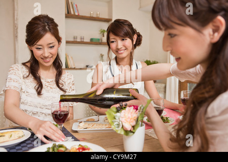Three Young Women Enjoying Wine at Party Stock Photo